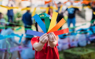 child holding rainbow colored papers PRIDE