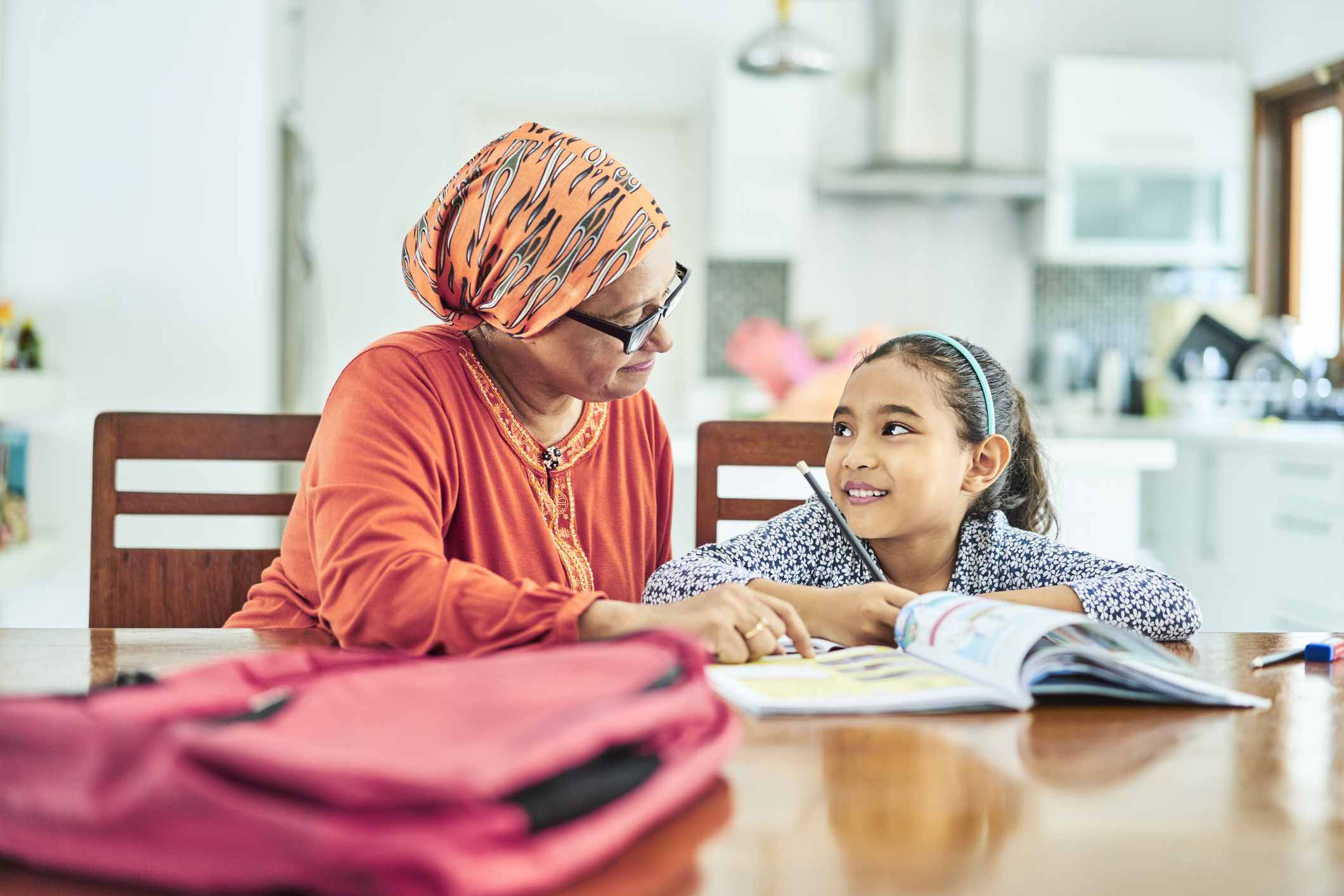 Grandmother assisting girl in studying at home