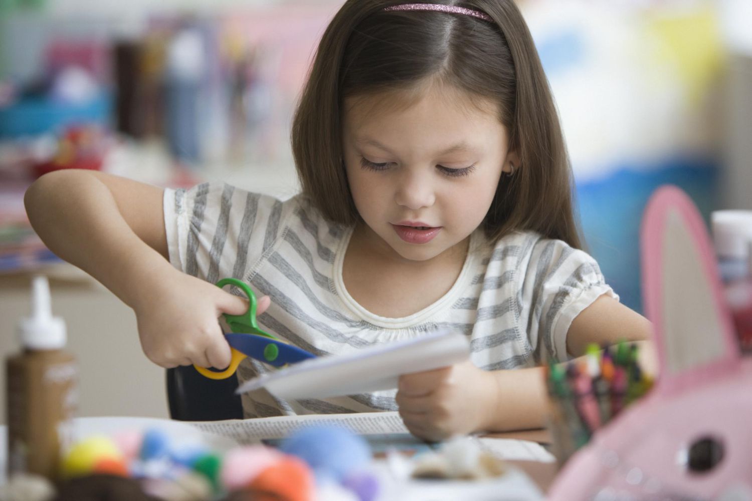 Young girl cutting paper to make a crafts project