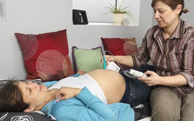 助产士使用多普勒胎儿监测器在子宫内检查婴儿的心跳