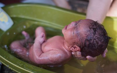 Newborn taking a bath at bathtub