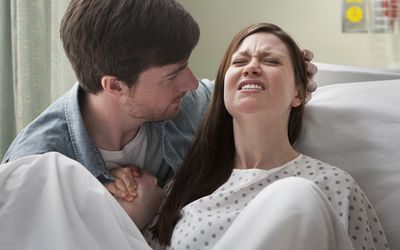 一个女人在医院里生孩子，一个男人牵着她的手