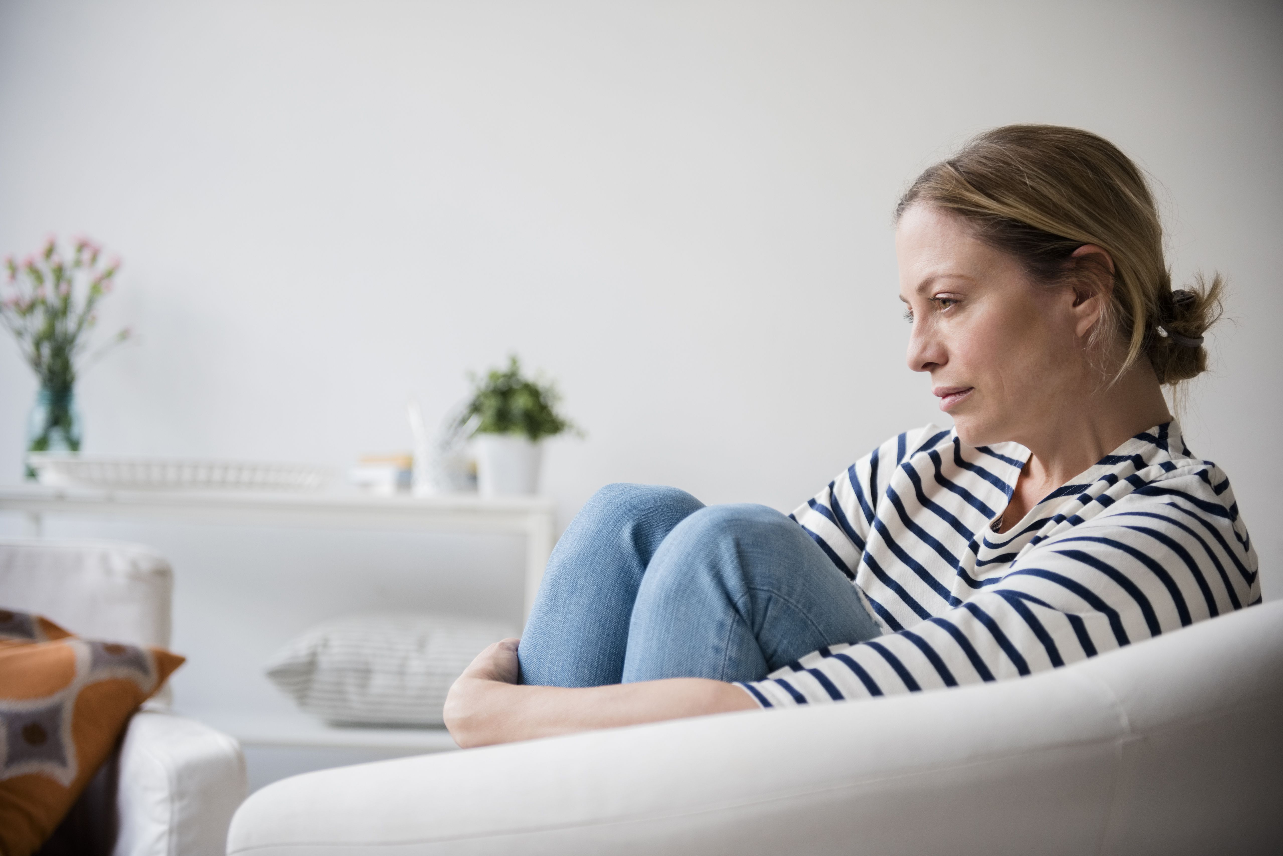 Caucasian woman sitting in armchair holding legs