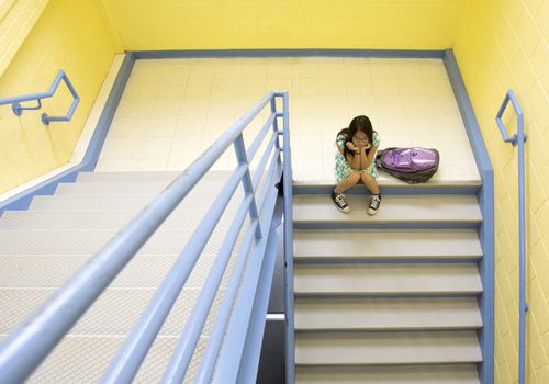 Bullied girl sitting on steps at school