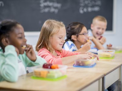 elementary age children are sitting at their desks and are eating their healthy snacks