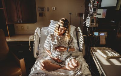 孕妇抱着肚子坐在医院的病床上