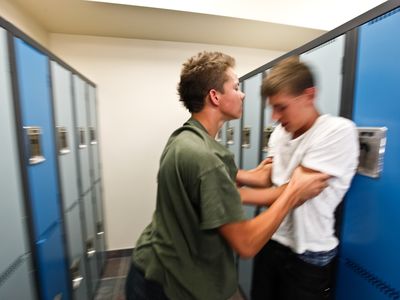 teenage bully roughing up another boy in a locker room