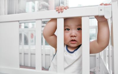 Baby boy looking through his crib