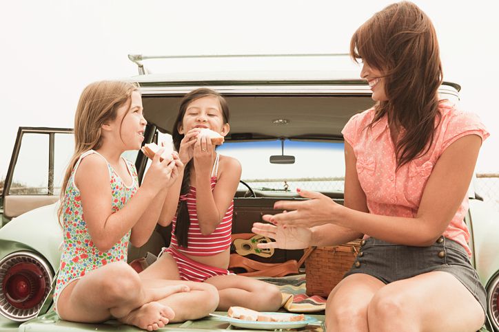 Mother and daughters having a picnic in the back of a station wagon