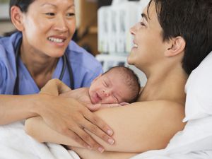 Nurse comforting mother and newborn in hospital