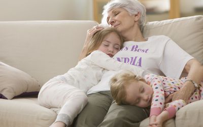 Caucasian grandmother and granddaughters napping on sofa together