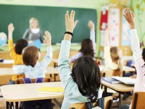 Children are raised hands in classroom.