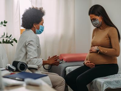 Doctor with a pregnant person in medical masks during an examinations.