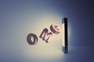 Letters O M G coming out from a cell phone screen, acronym you might find in fertility forums and social media sites