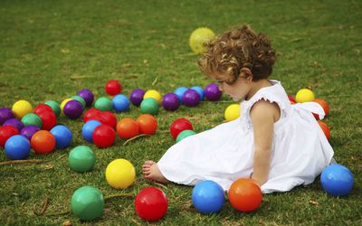 小女孩拿着五颜六色的塑料玩具球