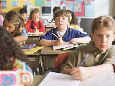 Attentive boy looking up from his desk in crowded classroom