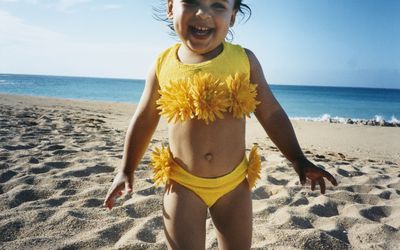 Smiling little girl in yellow swimsuit on a beach