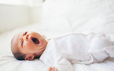 Baby girl yawning on bed