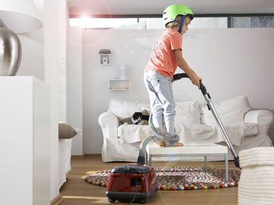 Boy in living room using vacuum cleaner