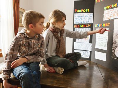 Two young kids looking at science project poster board