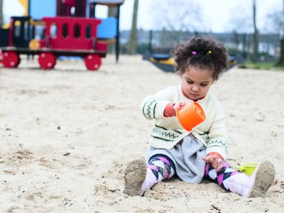 Toddler pouring sand from a cup