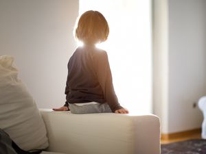 small boy sitting on couch arm facing away from camera