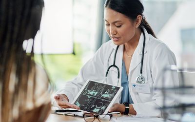 特写镜头:一名医生在她的办公室里向一名病人展示用数字平板电脑进行的超声波扫描