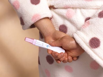 A tight shot of a woman's hands holding a positive pregnancy test