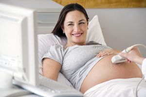 Pregnant Hispanic woman looking at ultrasound monitor