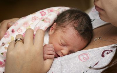 刚出生两天的早产女婴，躺在母亲的乳房上