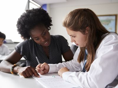 高中导师在课桌上给穿制服的女学生一对一辅导