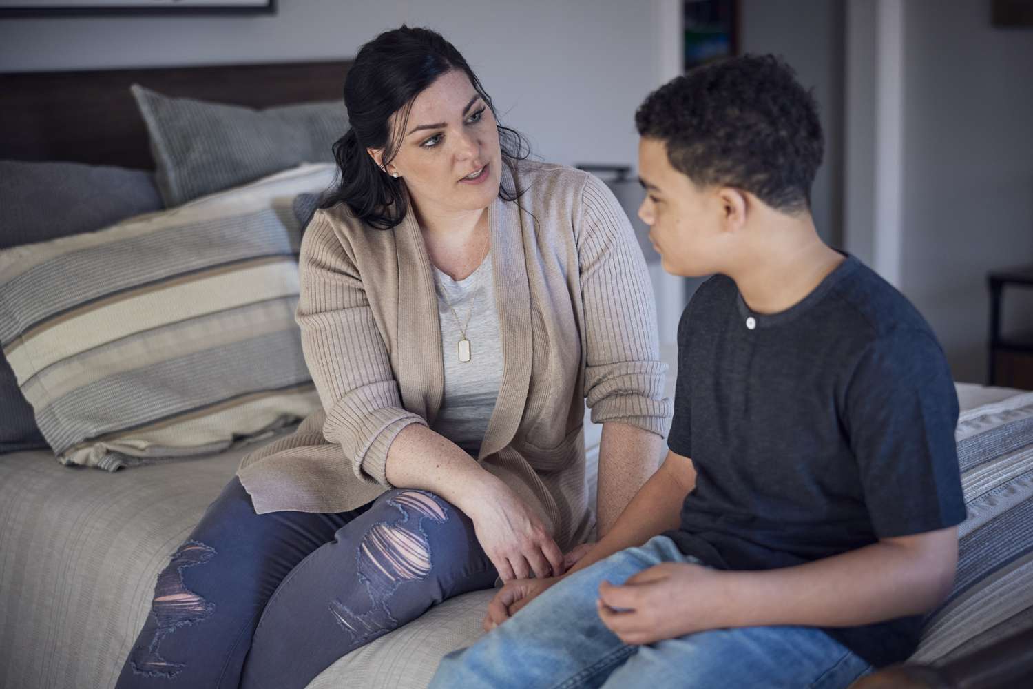 Mom and son sitting on bed talking