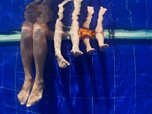 “有趣的水下照片，妈妈和孩子的腿在游泳池里
