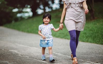 Little girl strolling in park with mom joyfully