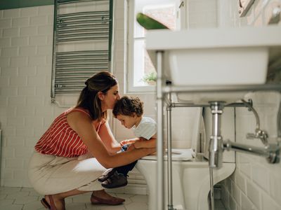 Mom helping toddler on the toilet