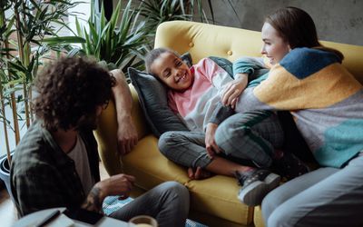 Foster parents watching TV with foster daughter