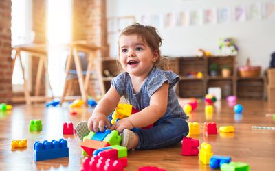 toddler sitting on the floor playing with building blocks