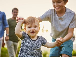 Older brother helping baby sister to walk