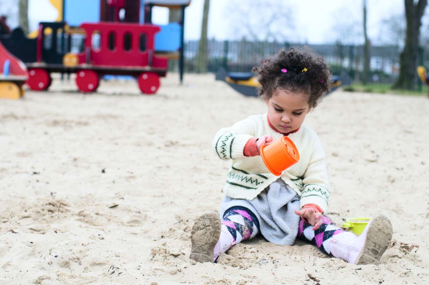 Toddler pouring sand from a cup