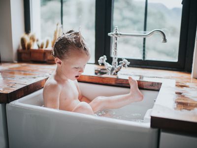 young boy bathing in kitchen sink