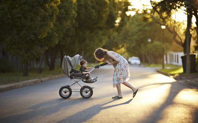 母亲和儿子推着婴儿车在夕阳下散步