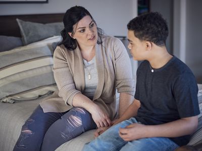 Mom and son sitting on bed talking