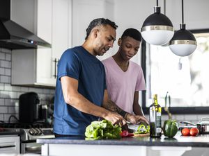 Father and teenage son cooking together in kitchen