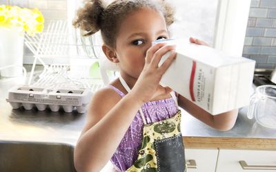 Young child drinking milk out of carton