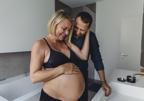 快乐的成熟孕妇夫妇在浴室看着准妈妈的肚子