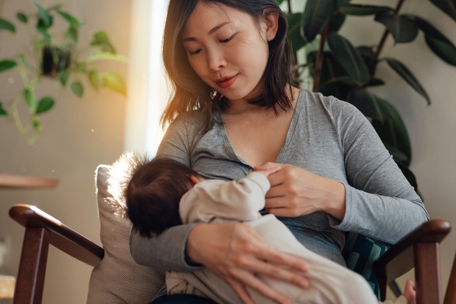 Mother breastfeeds her baby at home