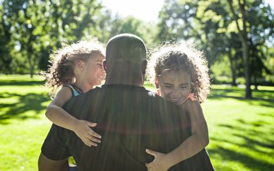 Father playing with twin daughters in park