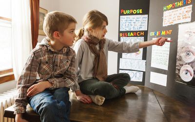 Two young kids looking at science project poster board