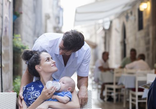 Woman feeding a baby at a sidewalk cafe