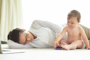 Mom and baby on the floor with a laptop and cell phone